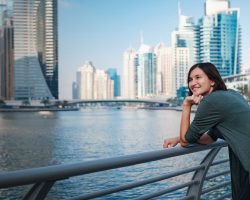 Happy young female traveler in the big city of Dubai, famous place Dubai marina. Luxury and comfortable tourism season in United Arab Emirates.